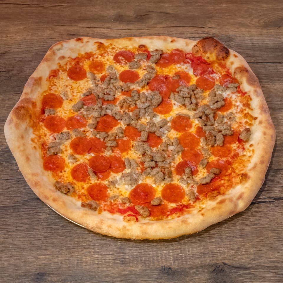 Big Oven Pizza's pepperoni and sausage pizza, with a golden crust, on a rustic wooden table.